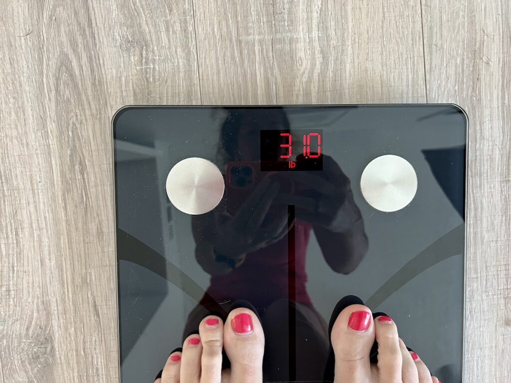 Person standing on the Renpho elis smart scale, reflected in surfaxce